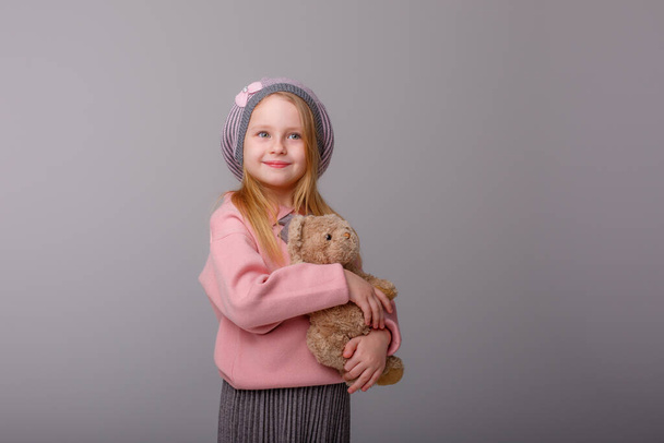 Nettes Mädchen posiert mit Teddybär gegen Grau - Foto, Bild