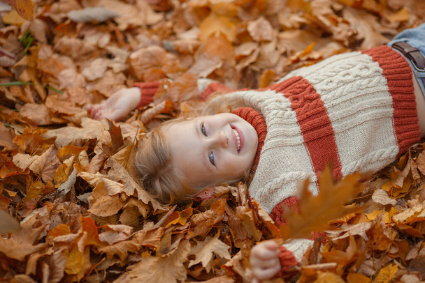 roztomilá holčička ležící na zemi a dívající se do kamery - Fotografie, Obrázek