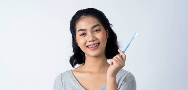 Asian teen facial with braces and smiling to camera to show dental orthodonic teeth which include professional metal wire material from orthodontist. studio shot white background. - Foto, imagen