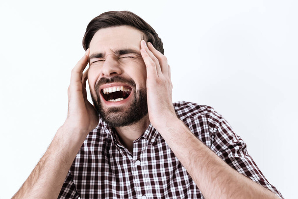 A man screams while he put his hands on sore head. - Фото, зображення