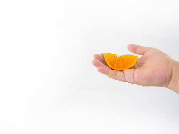 La main d'un homme tient une orange qui a été transformée en petites moitiés. Avec de fines rayures de pulpe d'orange fond blanc - Photo, image