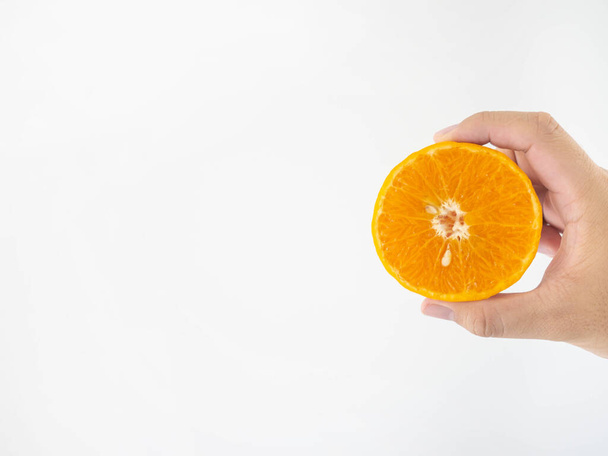 半回転のオレンジを持つ男の手パルプには大きなオレンジの種があります。オレンジパルプの細かい縞模様白の背景 - 写真・画像