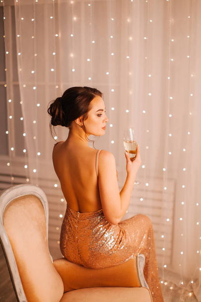 Girl in evening dress posing in the New Year's studio with a glass of champagne - Φωτογραφία, εικόνα