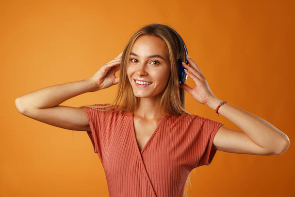 Positive young woman listening to music with blue headphones - Фото, изображение