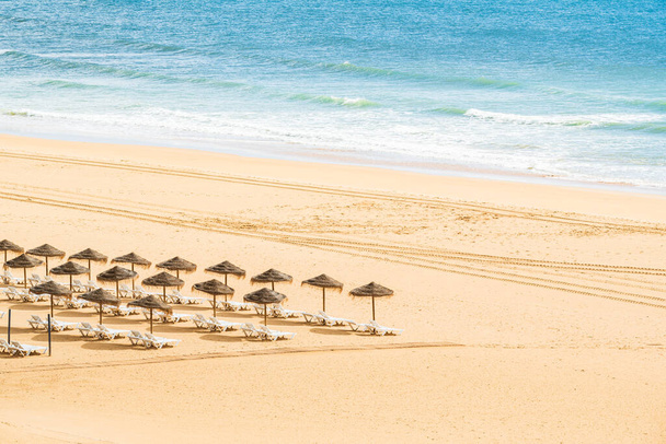 άδεια παραλία με ομπρέλες και πτυσσόμενες ξαπλώστρες στο βάθος. - Φωτογραφία, εικόνα