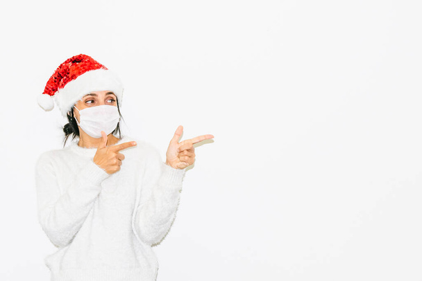Carino donna caucasica in abito di Natale punta il dito indice verso lo spazio bianco destro. Concetto di spazio vuoto per pubblicità e saluti. - Foto, immagini