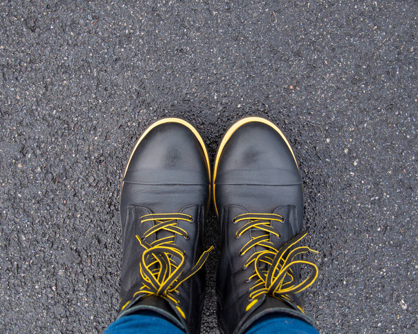 Casual preto botas amarelas de pé ao ar livre no asfalto - Foto, Imagem