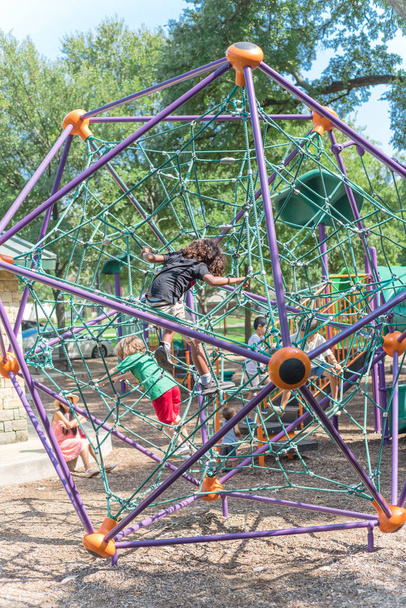 Multiethnic children climbing the web net at playground near Dallas, Texas, USA nature park - Photo, Image