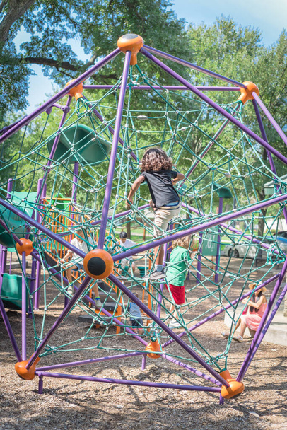 Crianças multiétnicas escalando a rede web no parque infantil perto de Dallas, Texas, EUA parque natural - Foto, Imagem