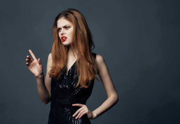 Red-haired lady in a black dress with red lips gestures with her hands, front view - Foto, immagini