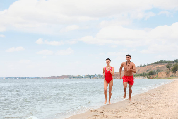 Professional lifeguards running at sandy beach on sunny day - Foto, immagini