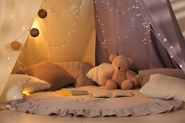 Tenda gioco con libri, cuscini e orsacchiotto. Camera moderna per bambini interno - Foto, immagini