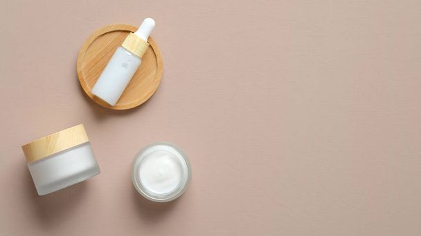 Set of natural cosmetic products on beige background. Flat lay serum dropper bottle and moisturizer cream jars. Organic beauty products top view. - Fotografie, Obrázek