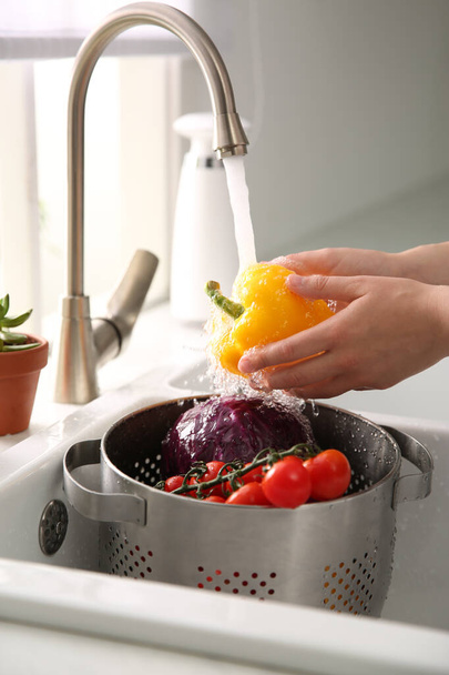 Woman washing fresh bell pepper in kitchen sink, closeup - Photo, Image