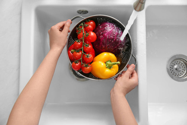 Woman washing fresh vegetables in kitchen sink, top view - Foto, imagen