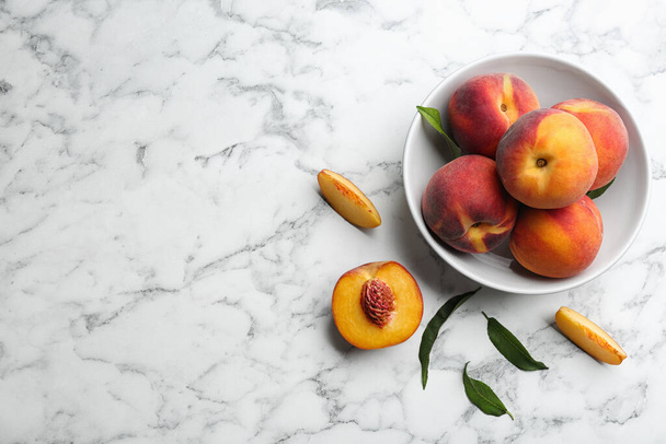 Fresh sweet peaches on white marble table, flat lay. Space for text - Foto, Bild