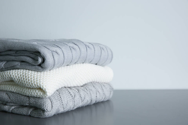 Stack of folded knitted sweaters on grey table. Space for text - Foto, imagen