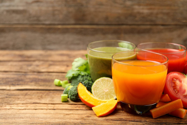 Delicious vegetable juices and fresh ingredients on wooden table. Space for text - Foto, Bild