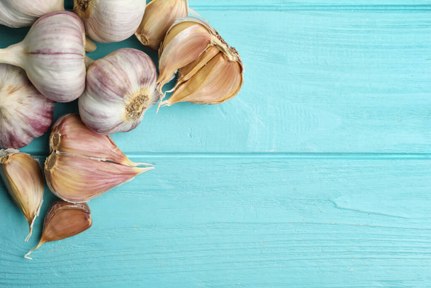 Fresh unpeeled garlic bulbs and cloves on light blue wooden table, flat lay with space for text. Organic product - Φωτογραφία, εικόνα