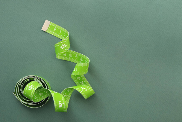 Measuring tape on green background, top view. Space for text - Фото, изображение