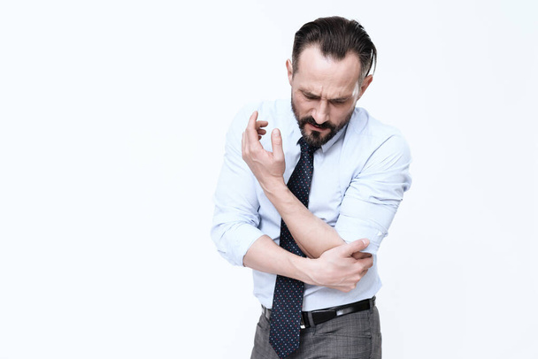 A man with a beard feels pain in the elbow.  - Valokuva, kuva