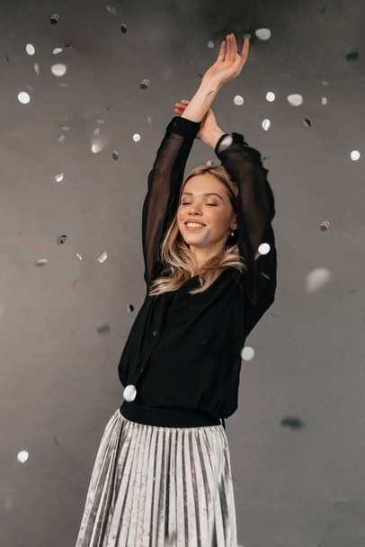Merry woman in holiday dress happy dancing and throwing out confetti, celebrating Christmas. Indoor photo of pretty lady having fun at new year party with pleased face expression. High quality photo - Foto, Imagen