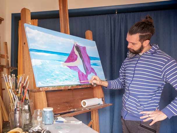 Varastossa kuva nuori mies taiteilija läähättää mereen sisätiloissa luonnonvaloa - Valokuva, kuva