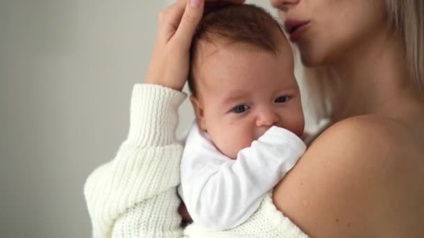 close-up van het gezicht van een pasgeboren baby, moeder houdt haar in haar armen en streelt haar hoofd - Video