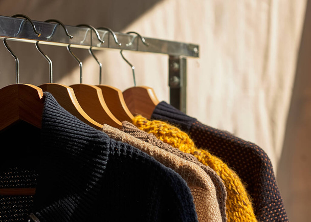 Otoño invierno temporada de punto. Coloridos suéteres de punto caliente con diferentes patrones de punto en percha riel de ropa abierta - Foto, imagen