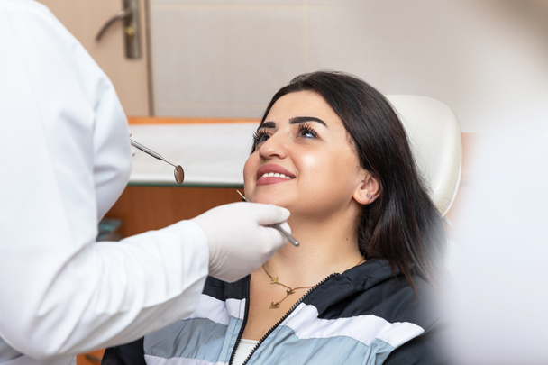 Mujer joven con una hermosa sonrisa en el dentista, mirando al médico - Foto, Imagen