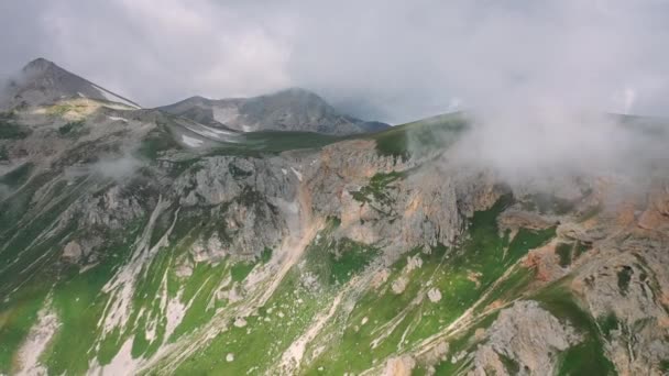 Epikus reggeli hegyvidéki táj fűvel borított lejtővel a felhők mozgó gőze alatt. Légi kilátás gyönyörű kaukázusi hegyek. Csodálatos hely a turisták számára. Utazási és túrakoncepció - Felvétel, videó
