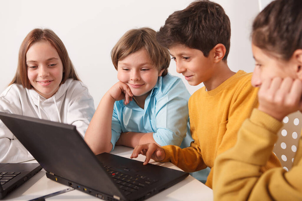 Cheerfu; niños disfrutando trabajando en un proyecto juntos, usando la computadora - Foto, imagen