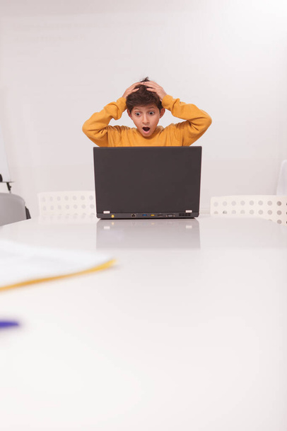 Вертикальний знімок маленького школяра, який виглядає наляканим і шокованим, стоїть перед комп'ютером, копіювати простір
 - Фото, зображення