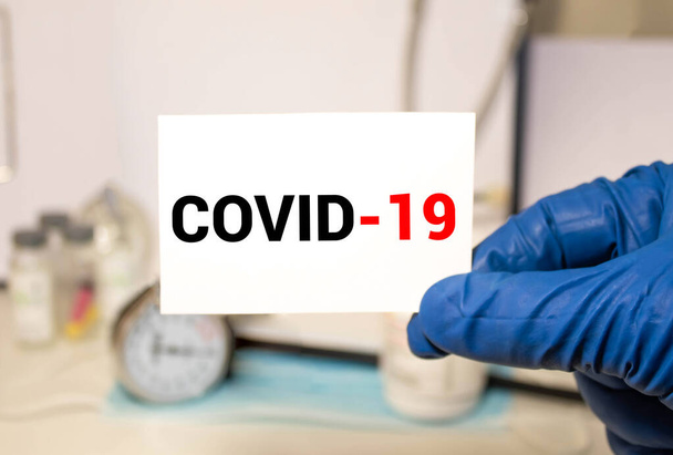 Een Aziatische vrouw van middelbare leeftijd met een medisch gezichtsmasker, met Covid-19 kaart. Aanmoedigen van de gezondheidszorg van Covid 19 Corona virus, op witte achtergrond. - Foto, afbeelding