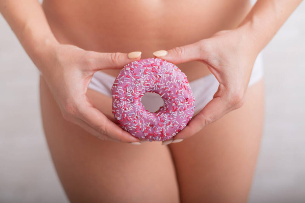 Faceless woman in white panties hold a pink donut - Foto, imagen