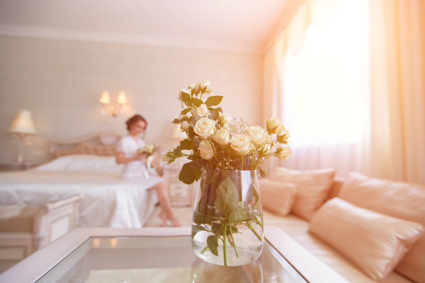 A pretty young girl. Bride's boudoir morning. Sitting on the bed with a bouquet of flowers. - Foto, Imagen