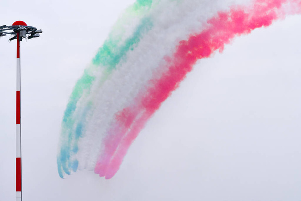 Frecce Tricolore оставляют в небе зеленый белый и красный дым, образуя полукруг - Фото, изображение