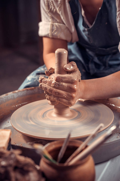 Hands of the master potter and vase of clay on the potters wheel close-up. Master crock. Twisted potters wheel. - Photo, Image