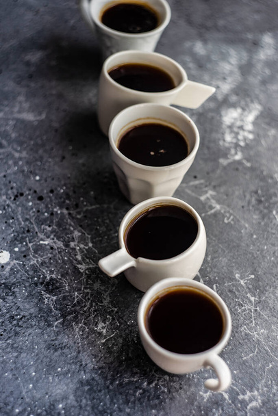 Keramické bílé hrnky s teplým kávovým nápojem na šedém textilním pozadí - Fotografie, Obrázek