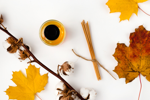 秋の雰囲気構成。空のグリーティングカードモックアップ。香水瓶、カラフルなカエデの葉。白いテーブルの背景。フラットレイアウト、トップビュー. - 写真・画像