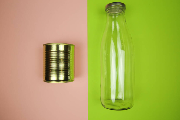 Bovenaanzicht op geïsoleerde metalen blik en glazen fles, roze en groen Achtergrond - afvalscheiding en recycling concept - Foto, afbeelding