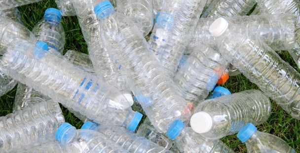 Pile de bouteilles en plastique avec une pelouse en arrière-plan. - Photo, image