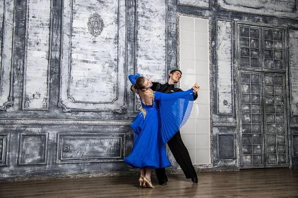 Nuori mies tanssii tytön kanssa sinisessä tanssisalissa mekko harmaa tanssisali - Valokuva, kuva