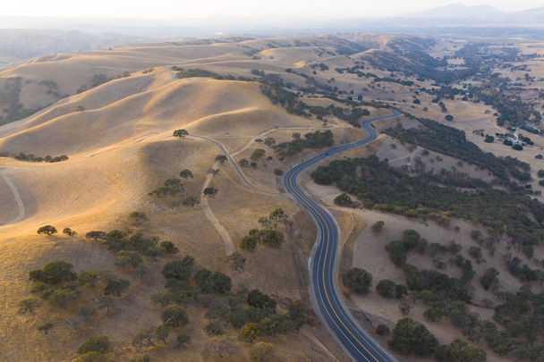 A scenic road meanders through the rolling hills of Northern California. These beautiful, eroded hills turn green once winter brings seasonal rain to the region. - Fotoğraf, Görsel