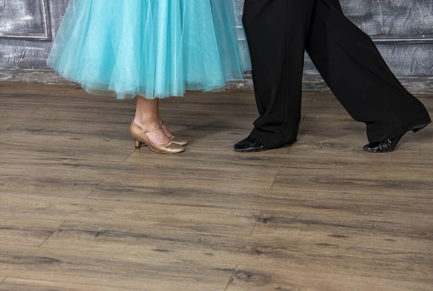 a young man in a black suit is dancing with a girl in a turquoise dress in the dance hall - Photo, Image