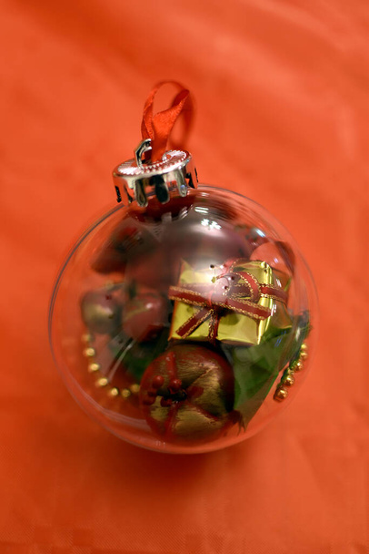 Christmas decorations, with sparling and blur efect. Glass christmas ball with gifts inside on red background - Photo, Image