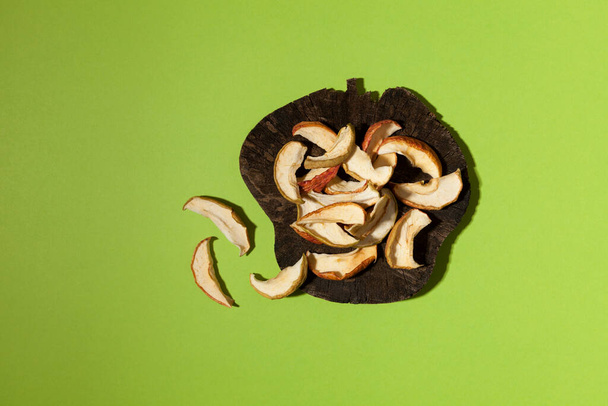 Homemade apple chips or dried apple slices on green background with copy space. Healthy vegetarian snack. - 写真・画像