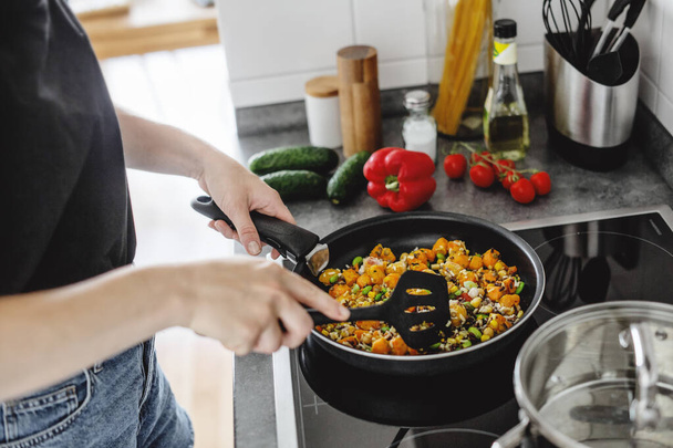 Young woman cooking fresh vegetables in pan at home. Healthy vegan or vegetarian concept.  - Fotoğraf, Görsel