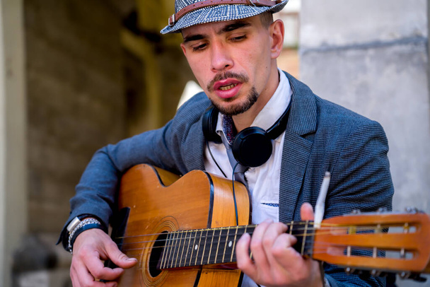 Straßenmusik-Kunst. Junger Mann spielt draußen auf der Straße in der Altstadt Gitarre. - Foto, Bild