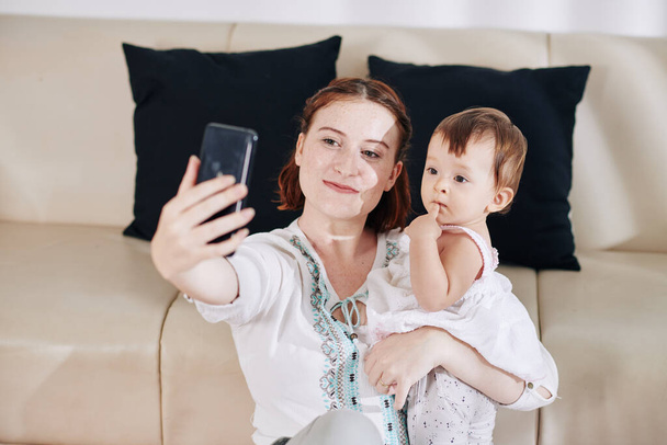 Feliz sonriente joven mujer tomando selfie con lindo pequeño bebé hija - Foto, imagen